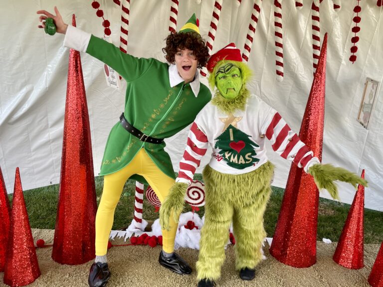 Two people dressed as an elf and the Grinch